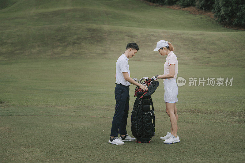 Asian chinese young couple golfer taking out golf club from golf bag on the golf course